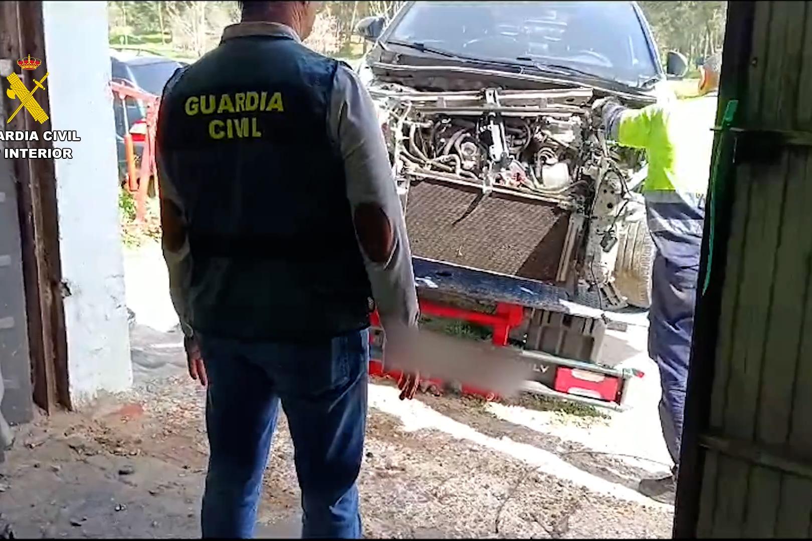 Imagen de un agente frente a un vehículo en proceso de despiece