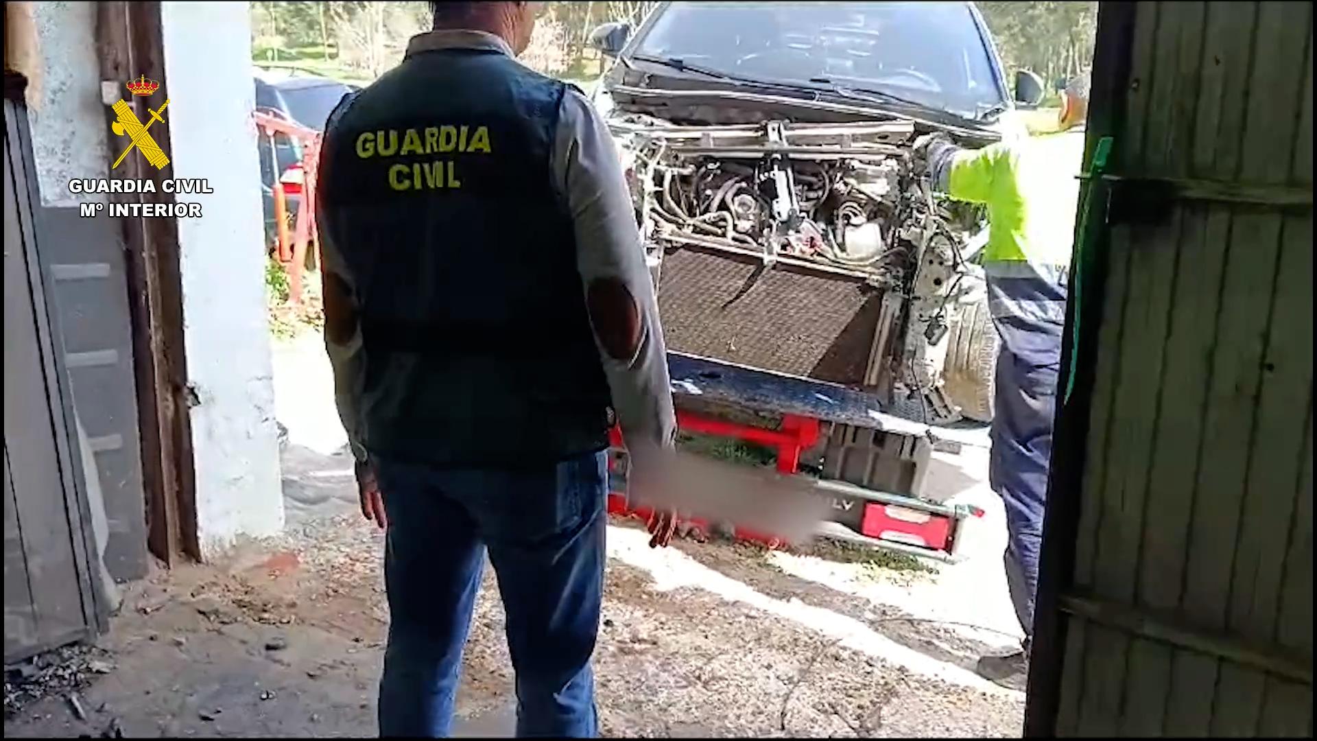 Imagen de un agente frente a un vehículo en proceso de despiece