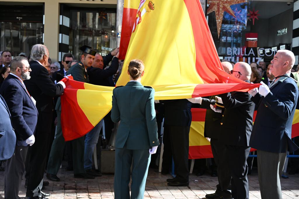 Participantes en el acto colocan la bandera de España