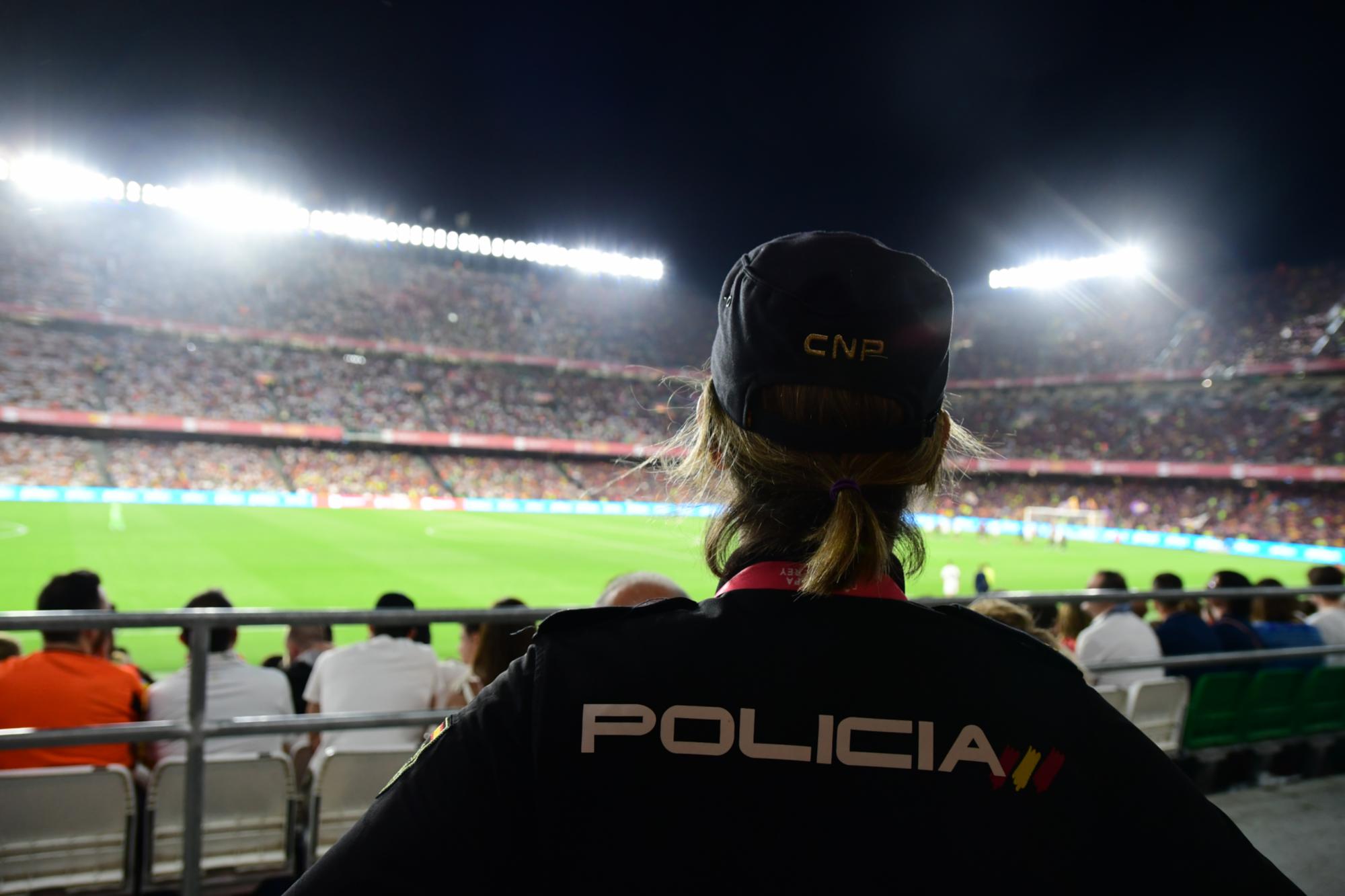 Agente de la Policía Nacional de espaldas en tareas de vigilancia de un partido de fútbol