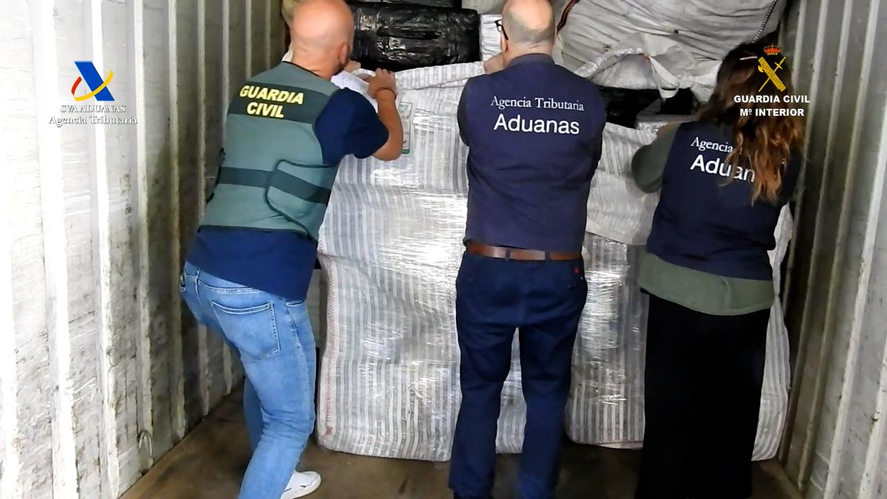 Agentes de la Guardia Civil y de la Agencia Tributaria descargando los fardos con hachís incautados en el puerto de Cádiz