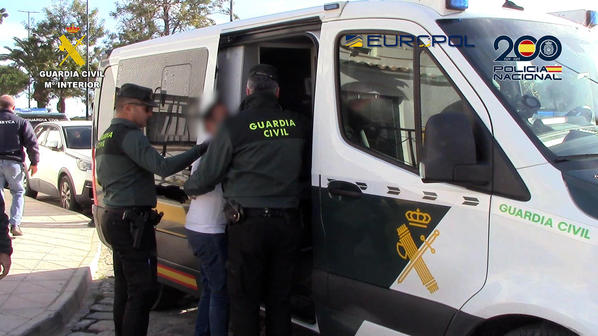 Agentes de la Guardia Civil trasladan a uno de los detenidos al vehículo policial